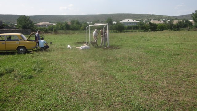 სკოლის მასწავლებლები და თემის წარმომადგენლები მუშაობენ ფეხბურთის კარების დასამონტაჟებლად.
Our school teachers and other volunteers are working on new stadium to place the football gates